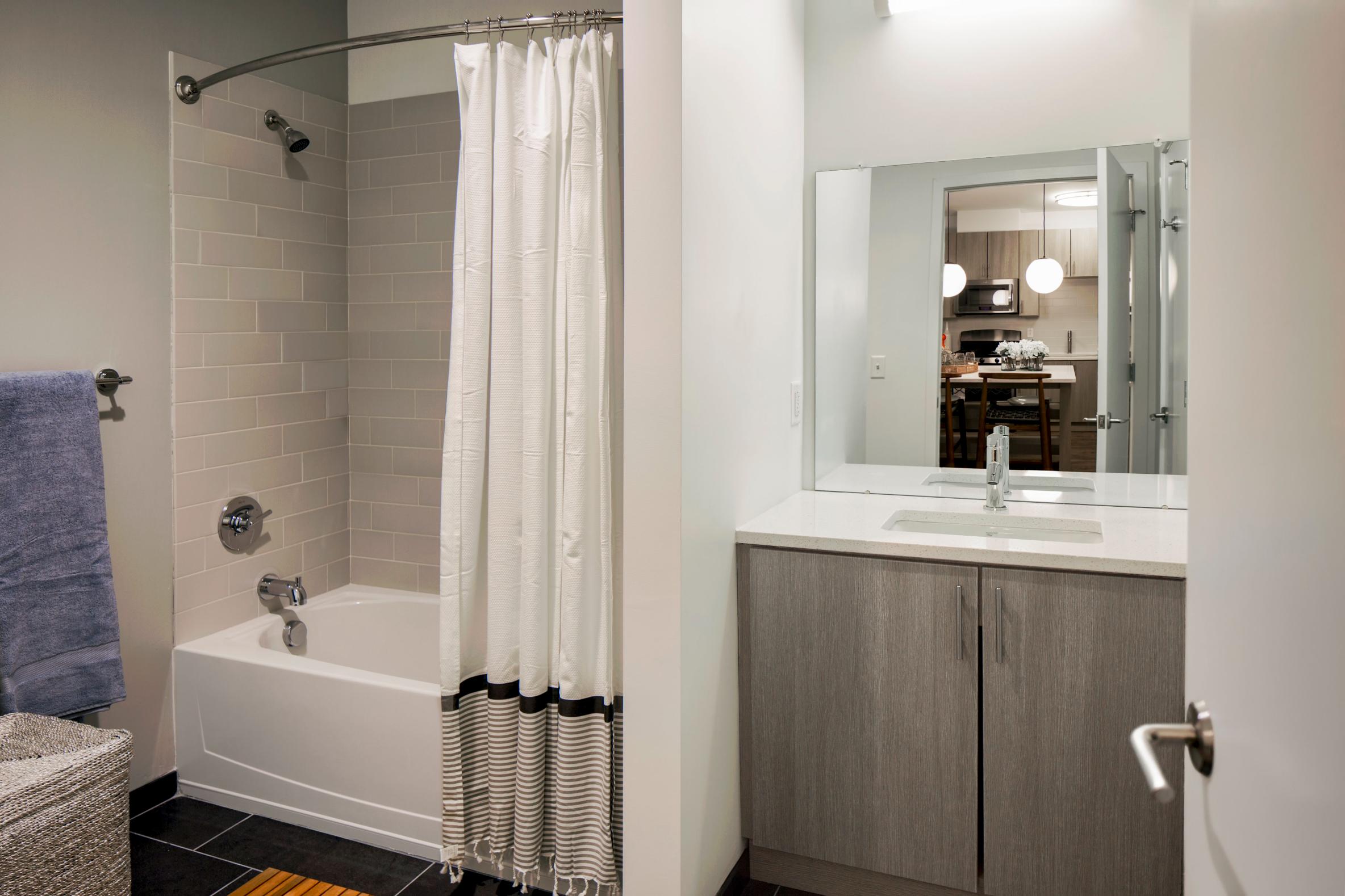 Bathroom featuring a shower/tub combo, a large mirror, and modern cabinetry