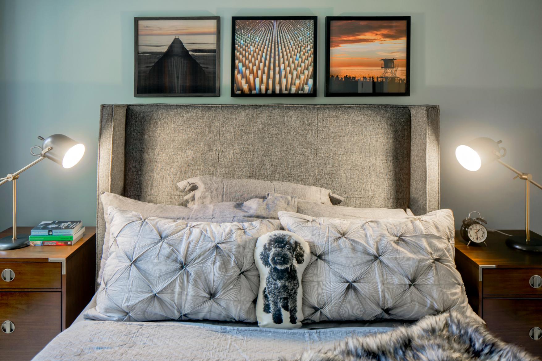 Close-up of a well-decorated bed with pillows and framed artwork above it