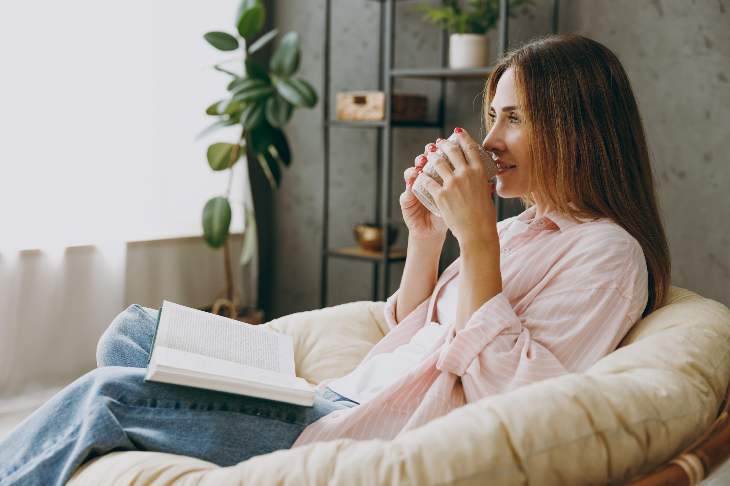 A woman sitting down, sipping a drink while relaxing.